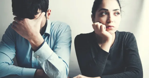 عائلة تجلس معاً على مائدة العشاء بينما أحد الوالدين ينظر إلى هاتفه، مما يرمز لتأثير التكنولوجيا على الوقت العائلي